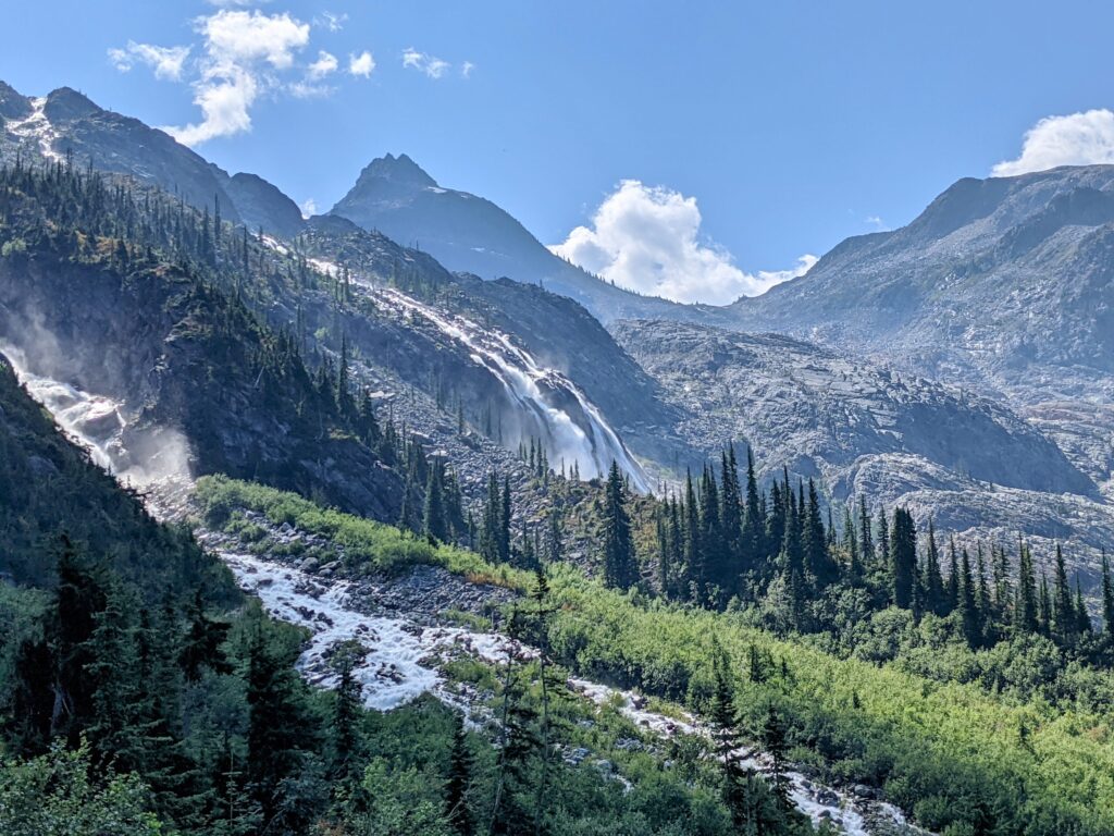 A scene of mountains, trees, a river, and a waterfall, from the Perley Rock hike in Glacier National Park, British Columbia