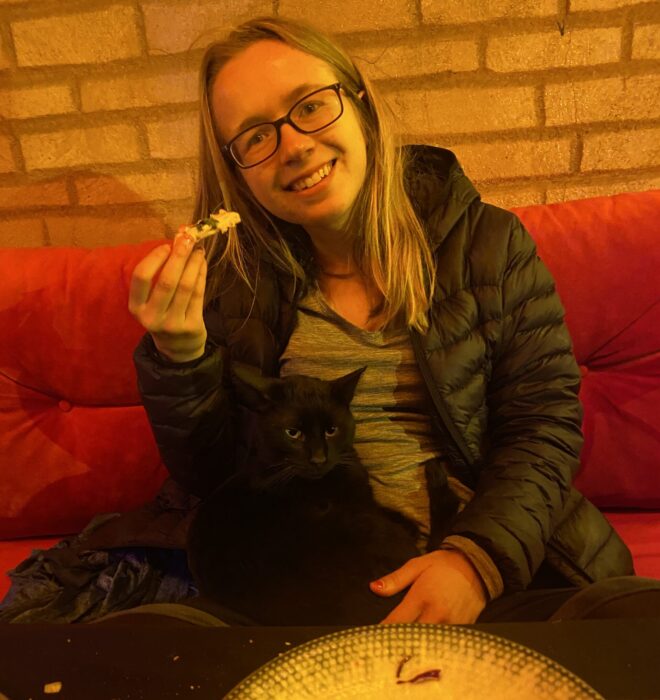 A woman in a restaurant in Istanbul with a black cat sitting on her lap.