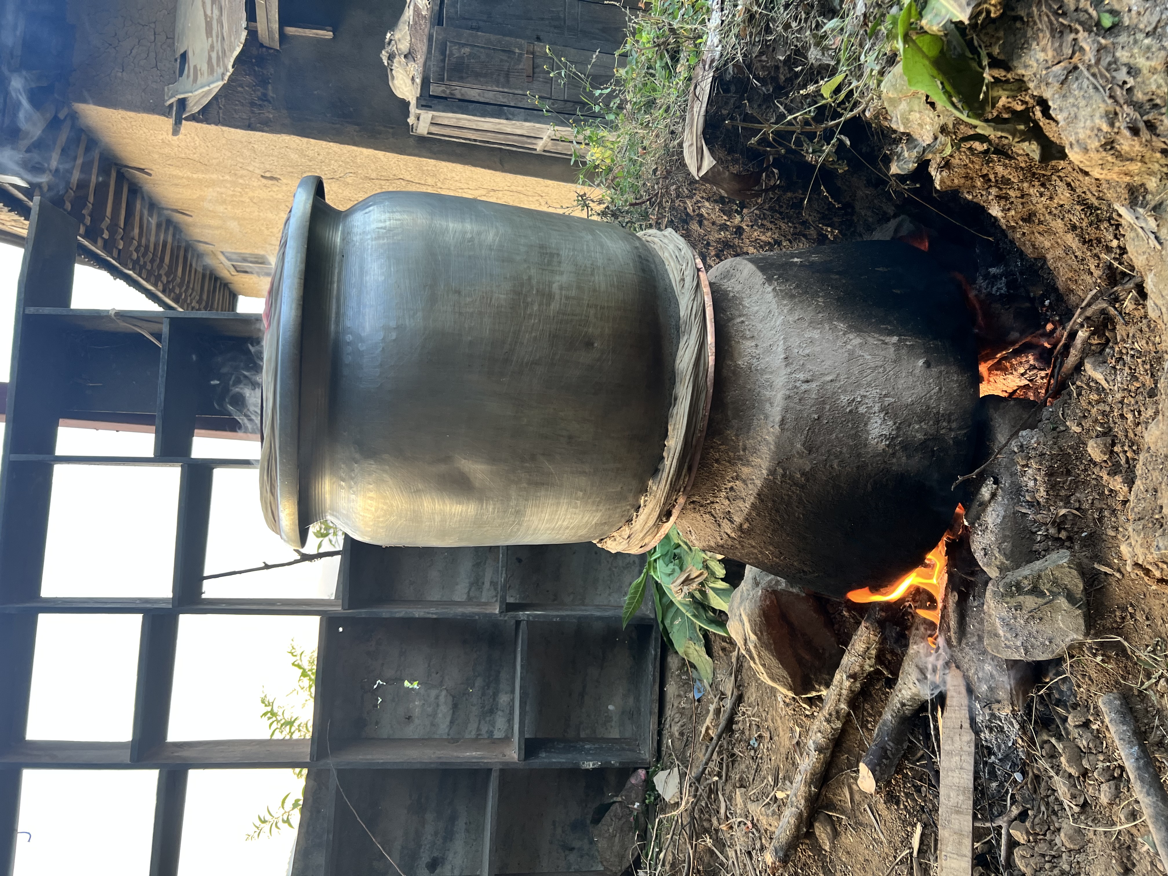 A large pot sitting onto of another pot, on top of a fire. 