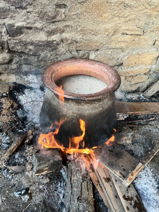 A large pot full of fermented rice, cooking on a fire. 