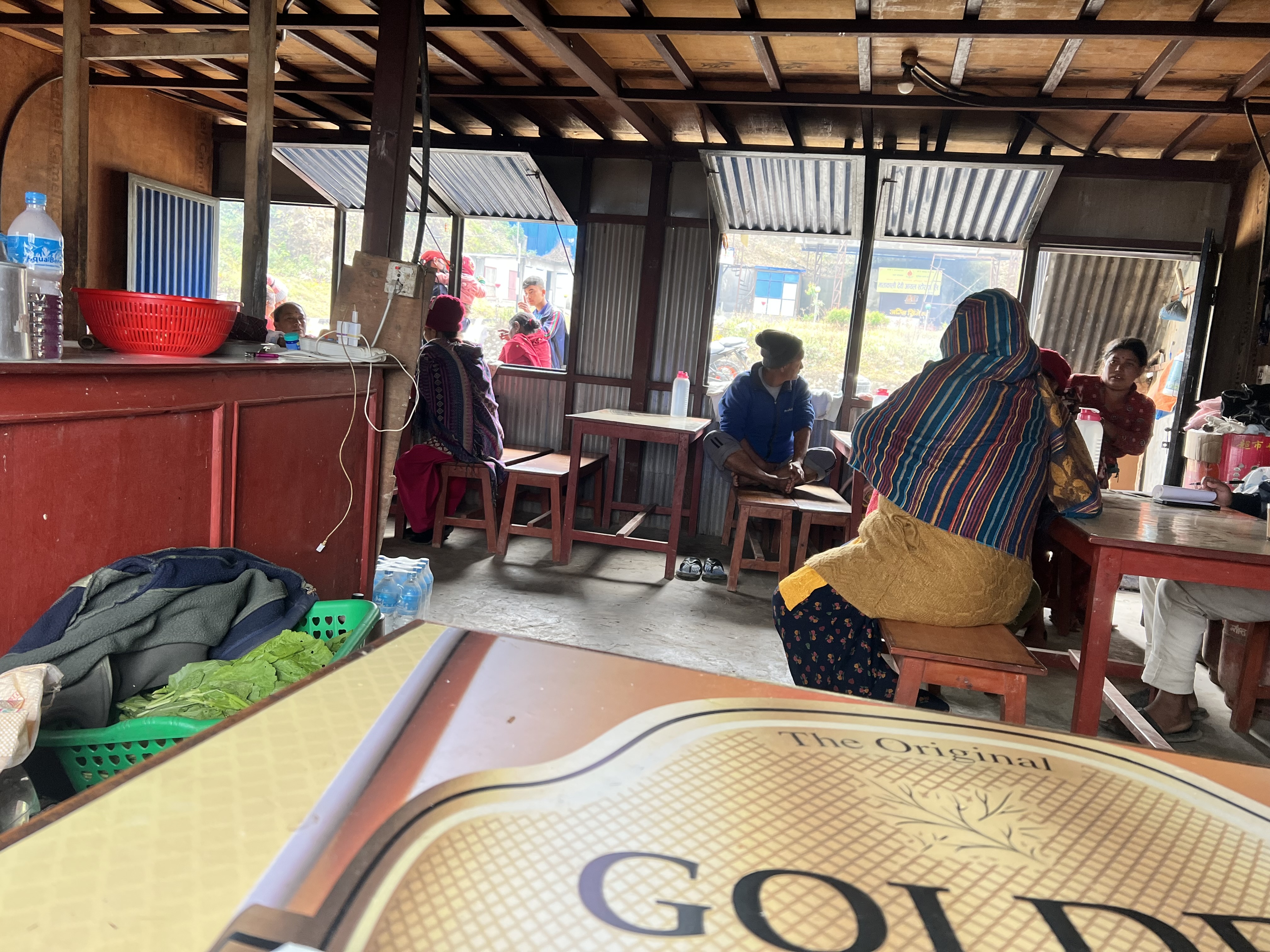 A picture of a restaurant in Nepal, with 4 people sitting at tables, taken from one of the seats in the back corner. 