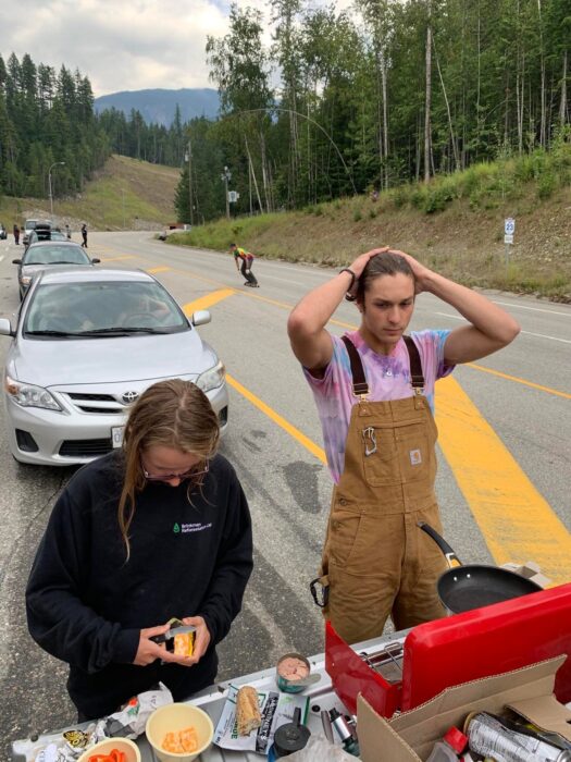 Two people cooking on a camp stove on the back of a truck to save money while waiting for a ferry in BC, Canada