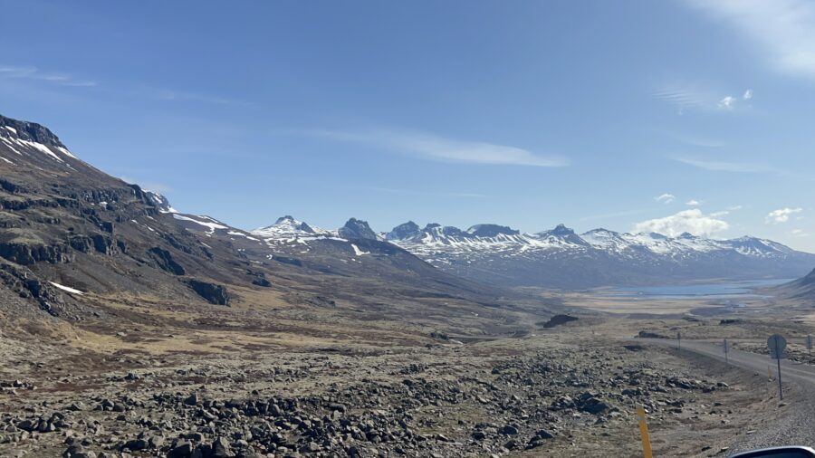 A road in Iceland, surrounded by mountains with snow on the tips