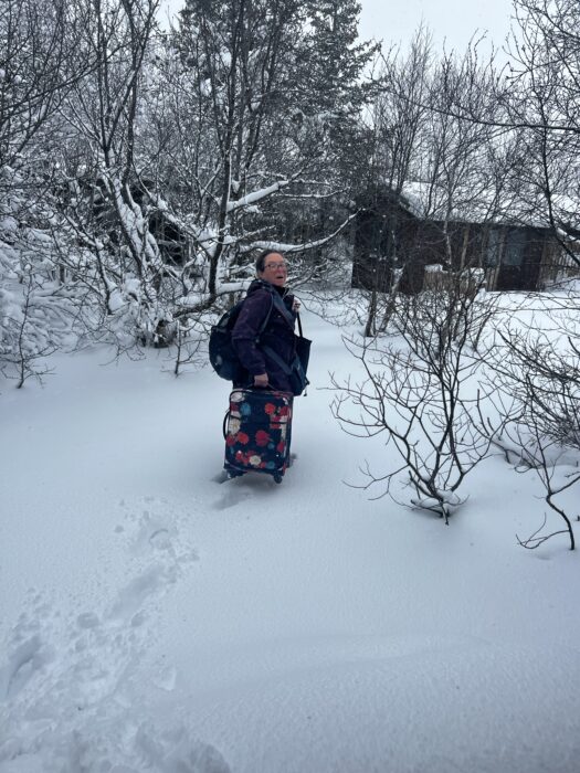 A women with a suitcase walking through deep snow during an unexpected snowstorm on a trip to Iceland.