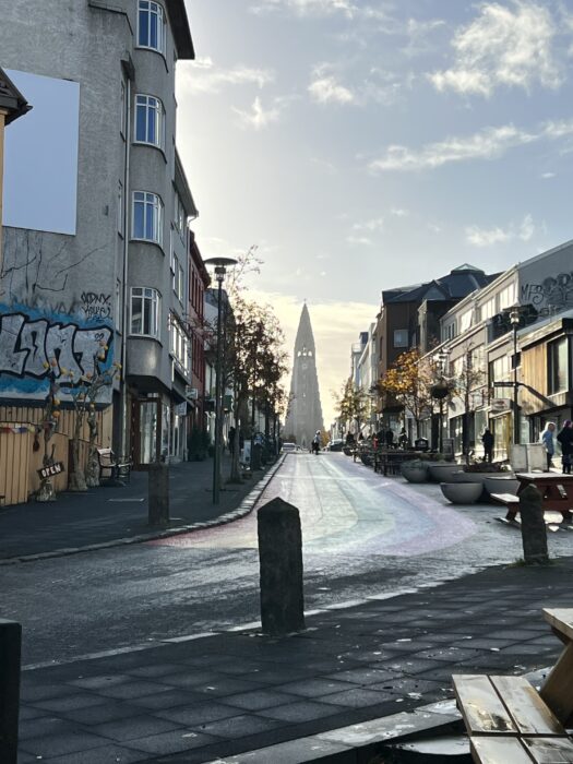 A city street in Reykjavik with a rainbow road, and Iceland's famous  Hallgrímskirkja church in the background.