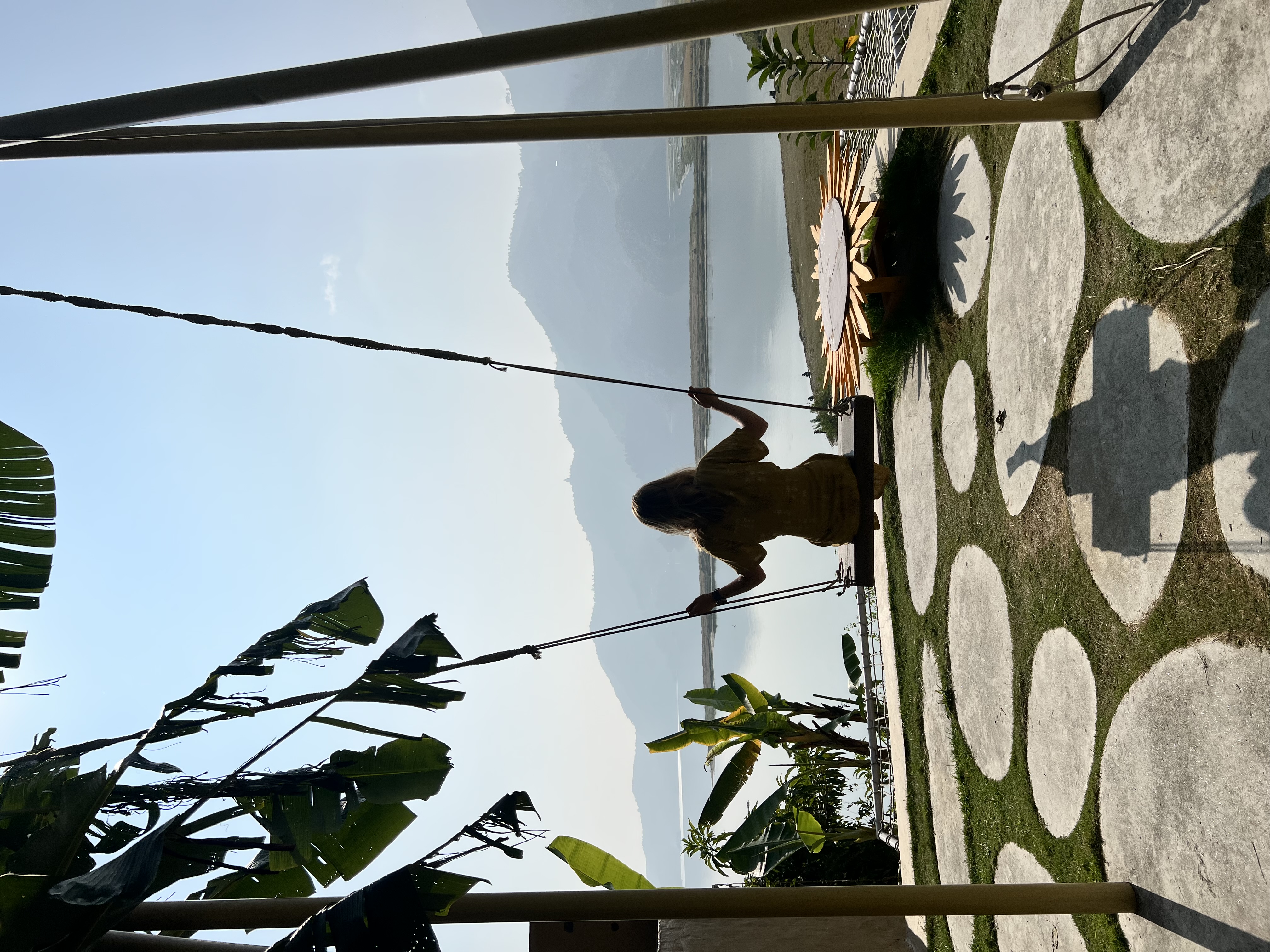 A girl swinging on a swing looking out at Phewa lake and mountains in Pokhara