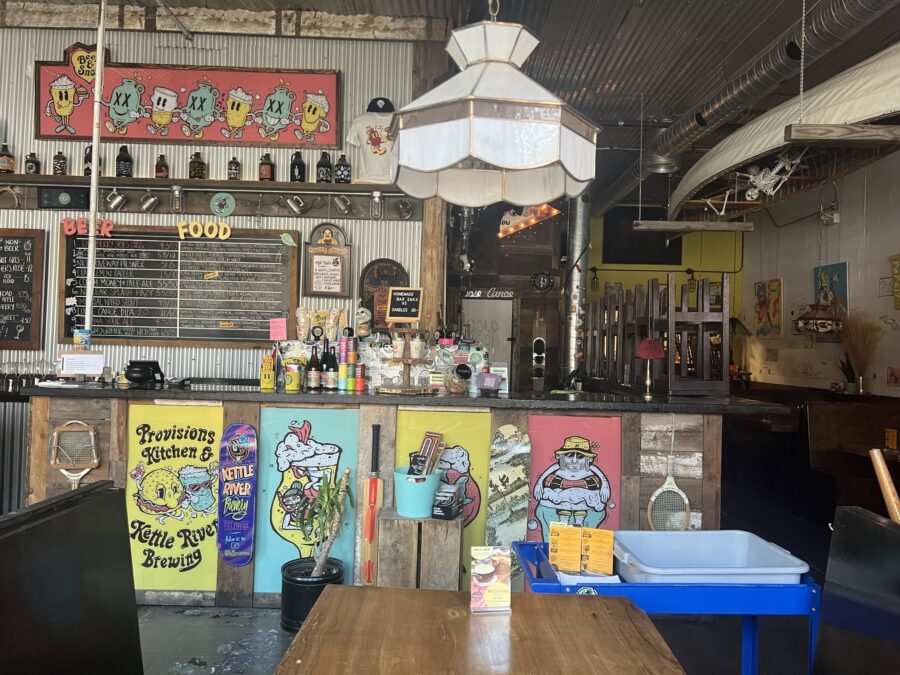 The inside of Kettle River Brewing. The counter is covered in colourful pictures. 