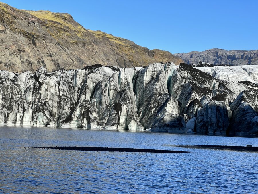 A large chunk of ice in the background with a body of water in the foreground