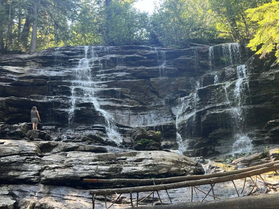 A girl looking up at a big waterfall, Moses Falls. 