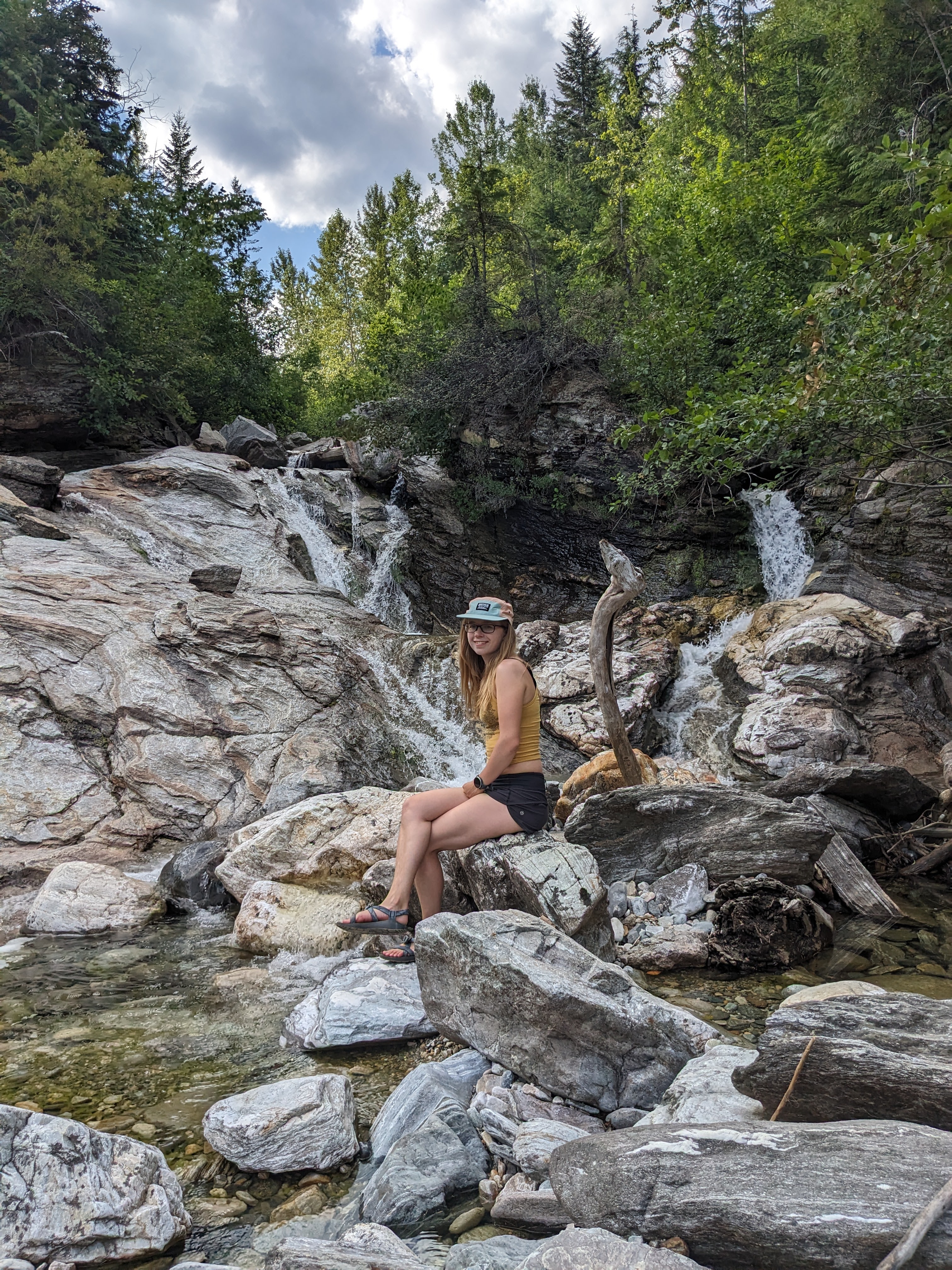 A girl sitting in front of a waterfall in Revelstoke. 