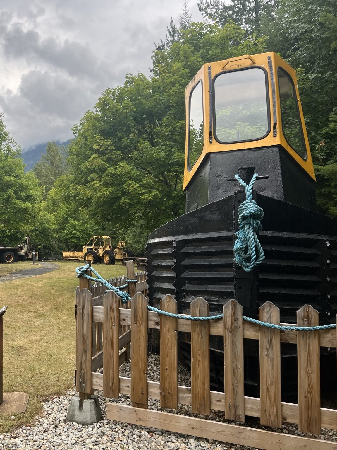 A tug boat, as viewed from the front, in a grassy yard with other machinery on display, outside the BC Interior Forestry Museum in Revelstoke