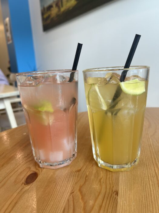 A glass of pink juice and a glass of a pale orange coloured juice