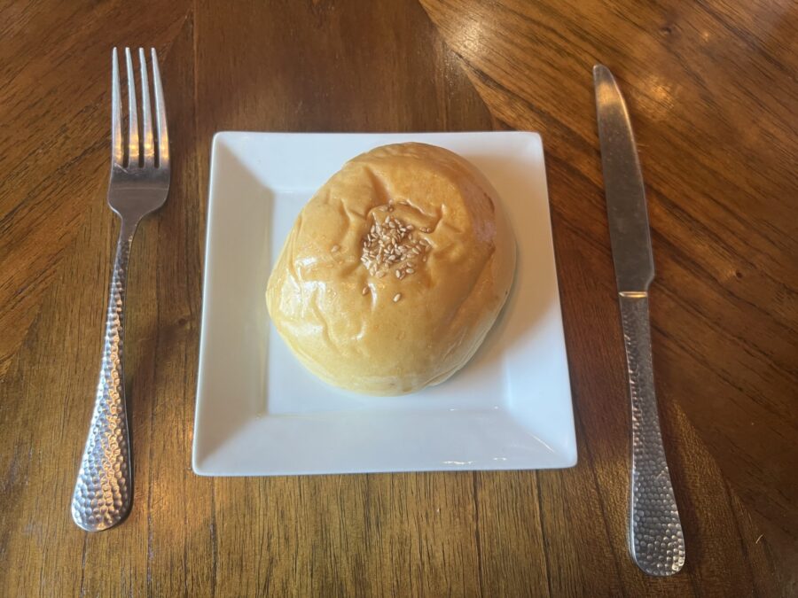 A dumpling bun from Conversations Coffee House on a plate with a fork and knife beside it