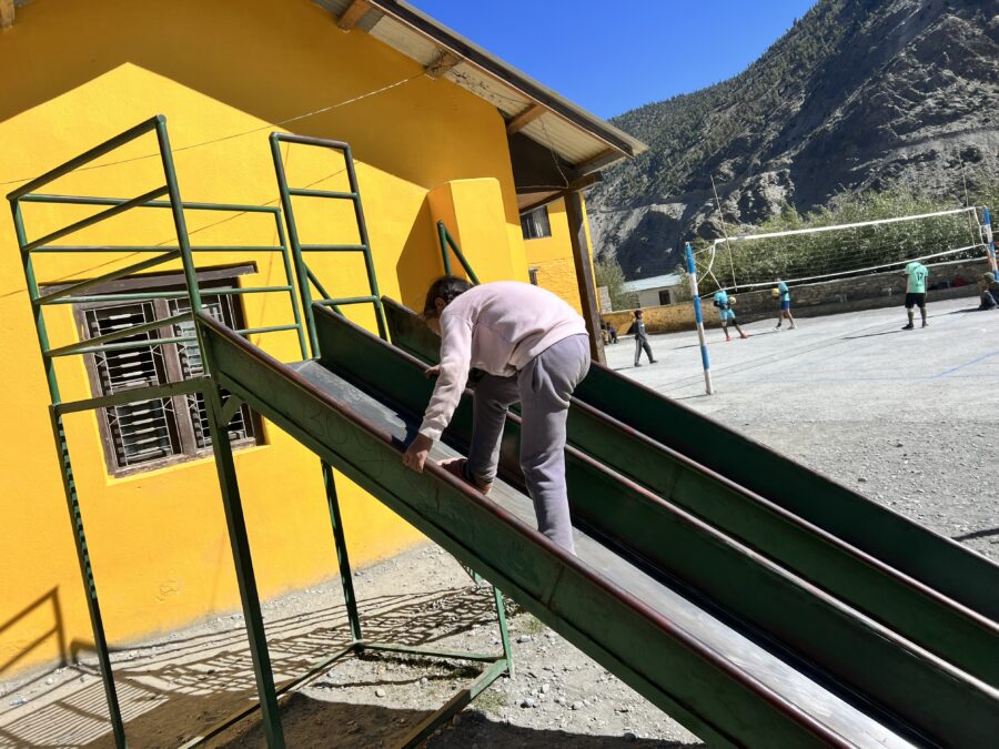 A girl climbing up a metal slide