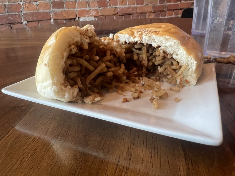 A dumpling bun from Conversations Coffee House cut open so you can see the noodles inside