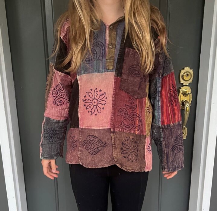 A dominantly purple quilt patterned shirt from Nepal, worn by a woman