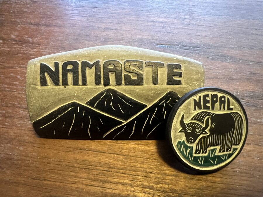 A stone carving that says "Namaste" and has mountains, with a smaller, magnet, stone carving that says "Nepal" and has a yak"