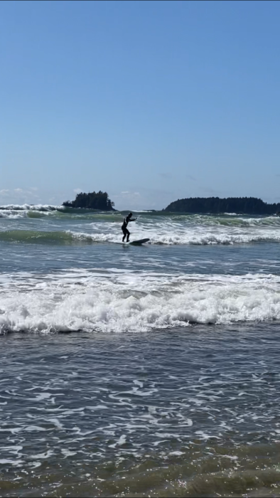 A first time surfer riding a small wave in Tofino. 