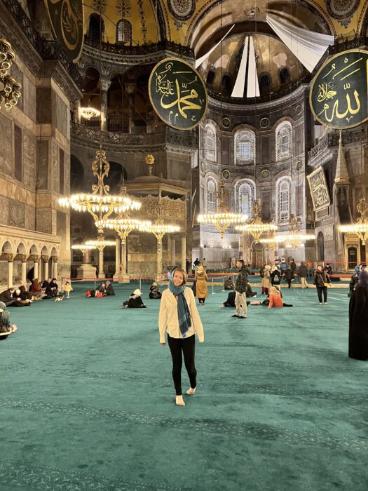 A girl in a blue head scarf standing in the Hagia Sophia. 