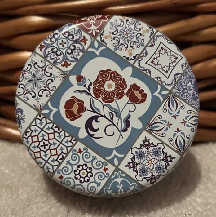 A round metal tin with intricate designs 